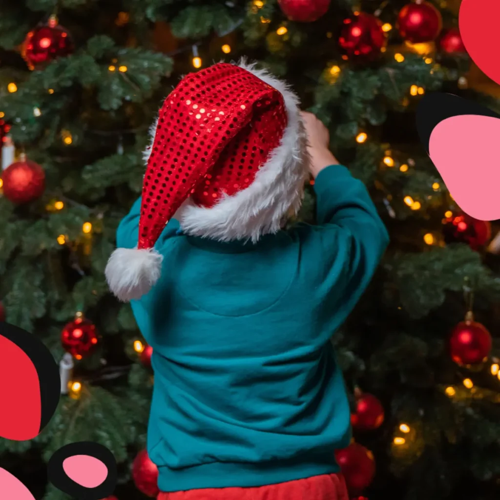 little boy hanging an ornament on a christmas tree to depict surviving Christmas during separation with kids