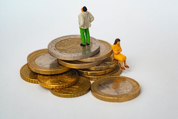 small family figures standing on large pound coins showing How To Cut Expenses On The Family Budget