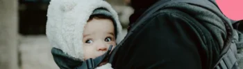 dad holding his baby in a sling while on paternity leave