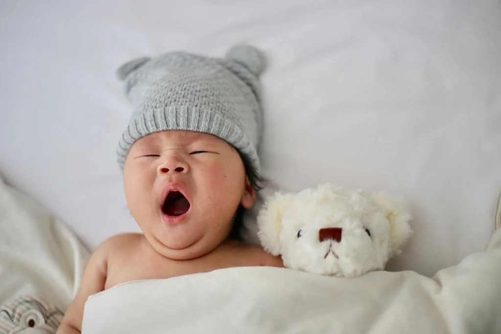 baby yawning with teddy in montessori crib