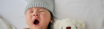 baby yawning with teddy in montessori crib