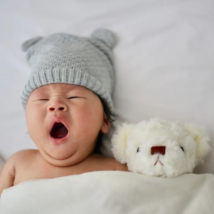 baby yawning with teddy in montessori crib