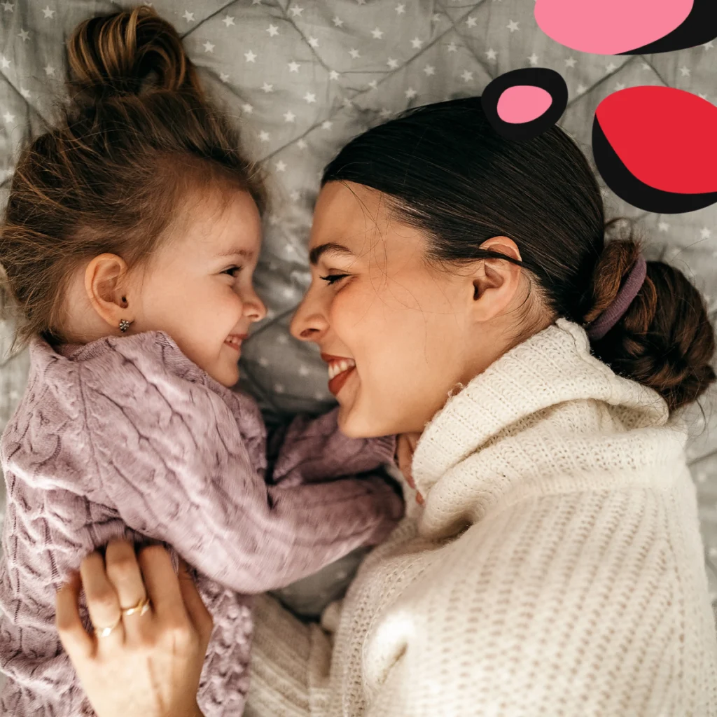 mum and toddler on bed smiling at each other face to face