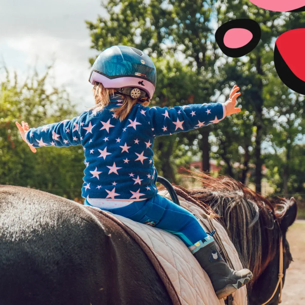 Toddler Equestrian Helmet on child riding horse with arms out