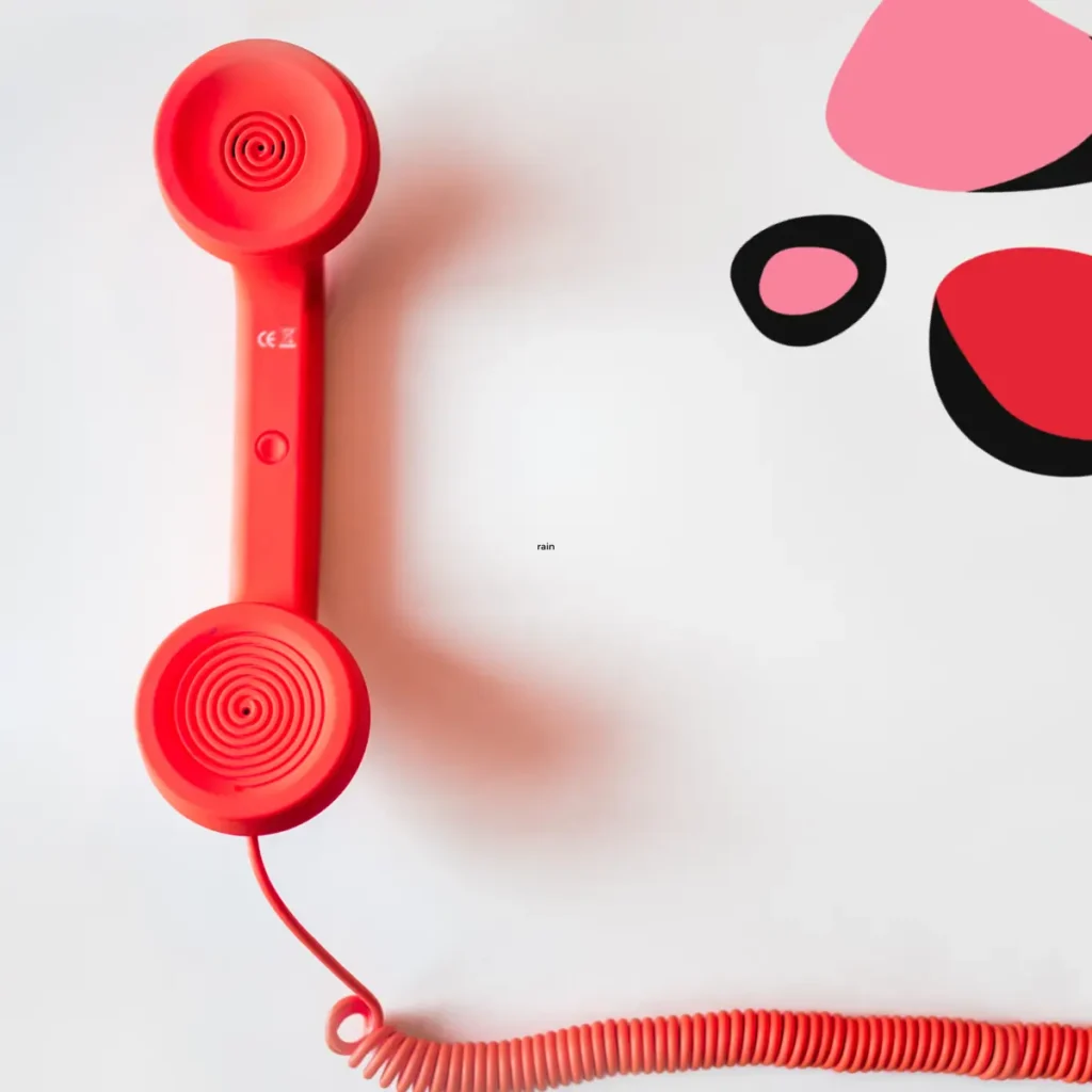 red phone handset with cord against white background as a telephone service