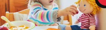 little girl feeding montessori doll at the table