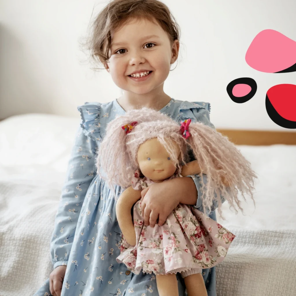 little girl in blue dress holding montessori doll in pink dress