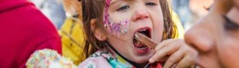 mum and daughter at a family festival in the uk with daughter eating ice cream and glitter on face