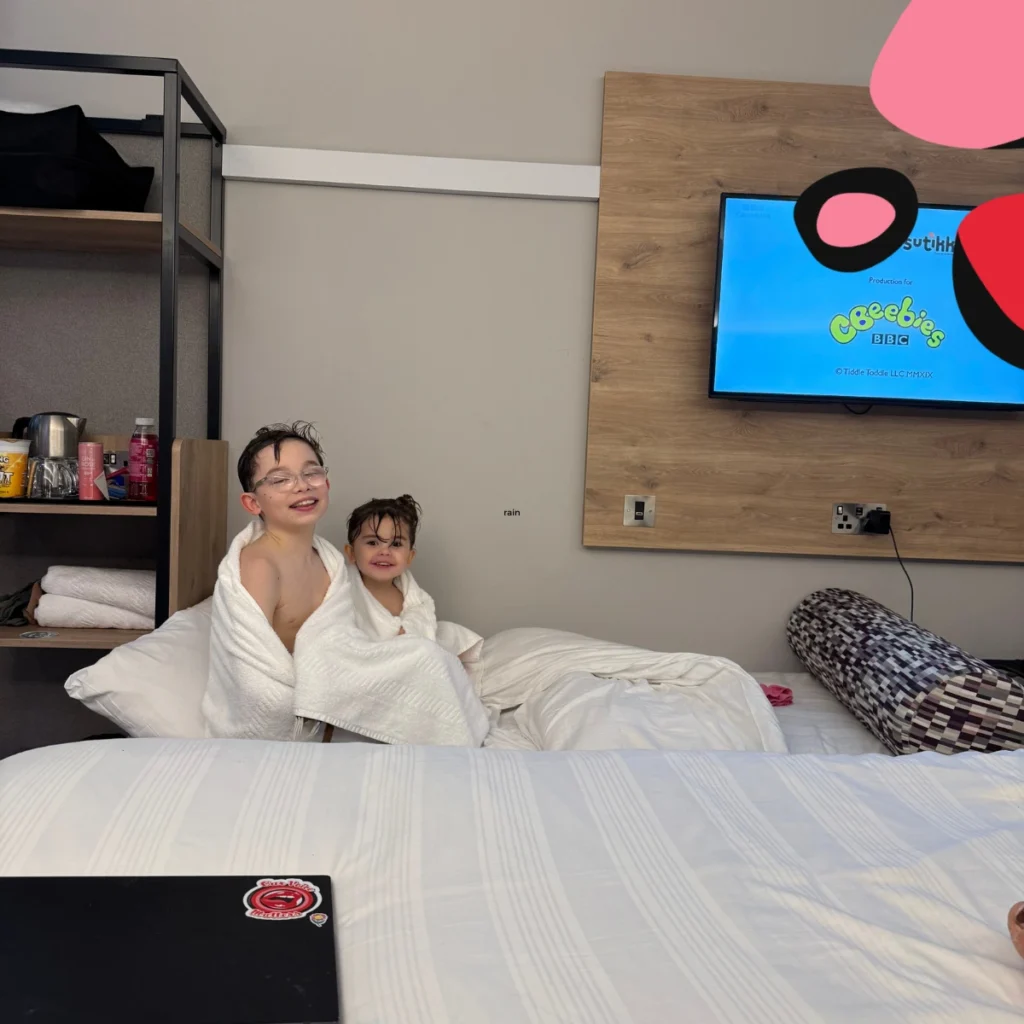 11yr old and 4 year old sitting on a bed watching tv at premier inn in glasgow