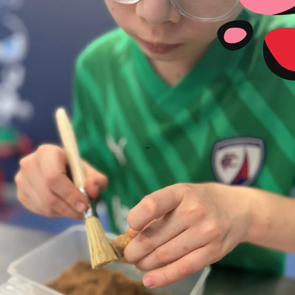 little boy uncovering a fossil with a paint brush at glasgow science museum