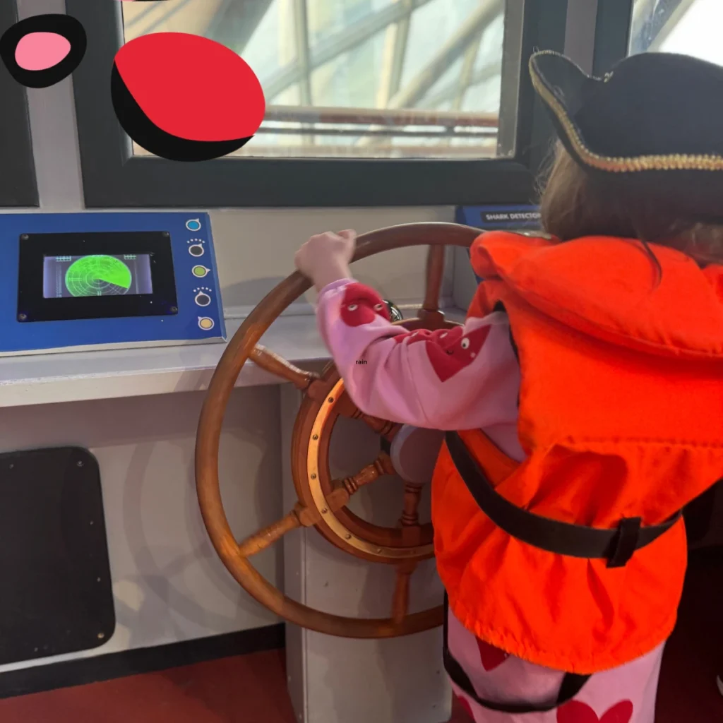 glasgow science museum with little girl in life jacket bright orange steering a ship