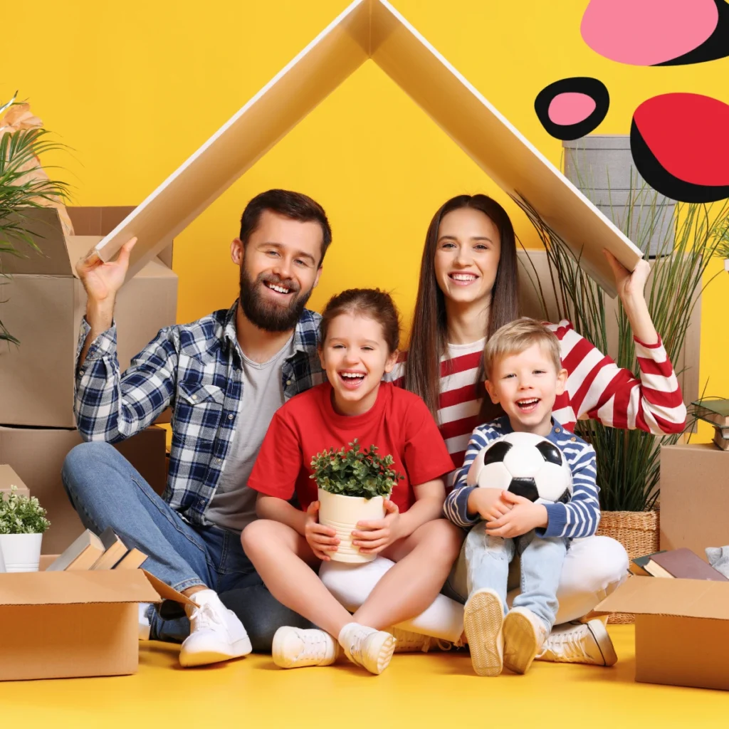 mum dad and kids sat against a yellow background with moving boxes and mum and dad holding a cardboard rook above them to show moving and relocating family