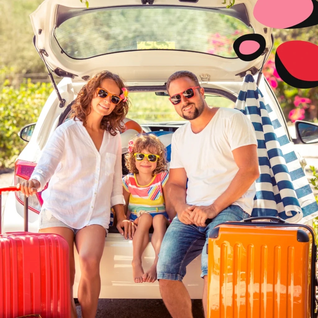 mum dad and kid sat in the back of the car boot with bright holiday cases ready for holiday in the sun